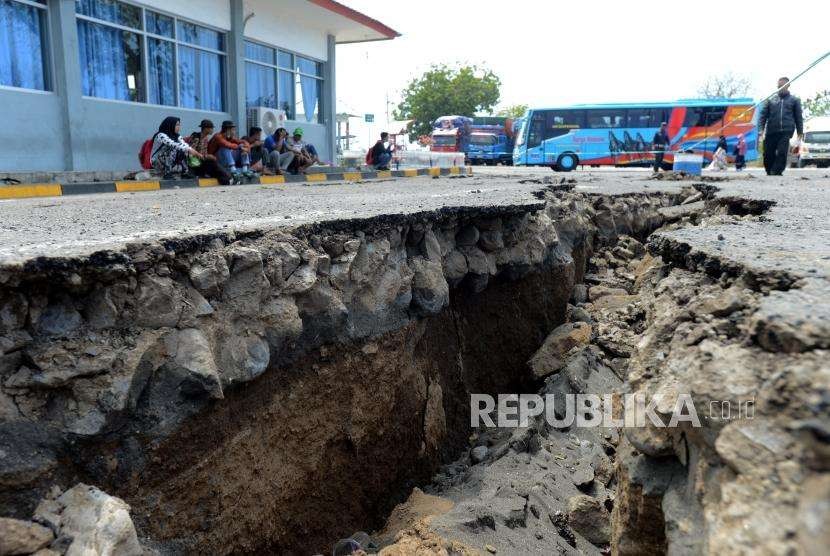Warga menunggu waktu keberangkatan di dekat area parkir ruang tunggu yang retak akibat gempa di Pelabuhan Kayangan, Lombok Timur, NTB, Selasa (21/8).