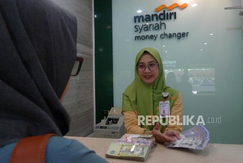 Seorang pegawai Bank Mandiri Syariah melayani nasabahnya saat melakukan penukaran uang Saudi Arabian Riyal (SAR) di Bank Mandiri Syariah Jakarta, Kamis (27/6).
