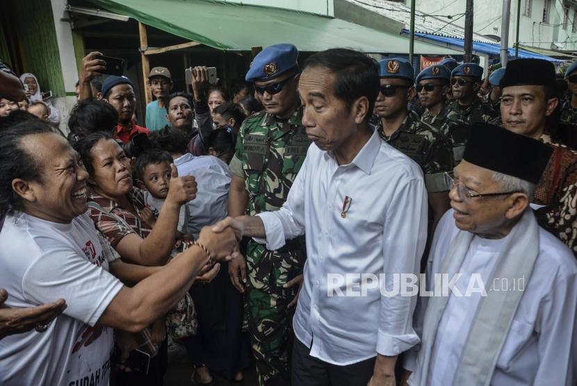 Capres Petahana Joko Widodo (tengah) bersama Cawapres Ma’ruf Amin (kanan) menyapa warga usai pidato kemenangan sebagai Presiden periode 2019-2024 di Kampung deret,Tanah tinggi,Johor baru, Jakarta Pusat, Selasa (21/5).