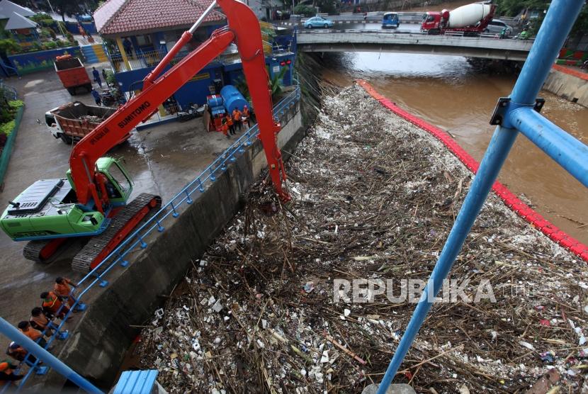 Petugas Dinas Lingkungan Hidup Pemprov DKI Jakarta mengoperasikan alat berat mengangkut sampah yang menumpuk di Pintu Air Manggarai, Jakarta, Ahad (8/4).