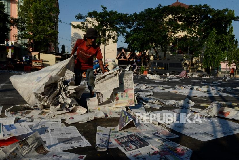 (ILUSTRASI) Petugas kebersihan membereskan koran yang digunakan alas saat pelaksanaan sholat Idul Fitri. 
