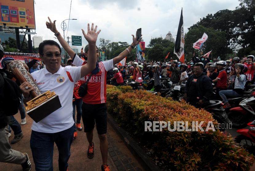 Salah satu pengurus Persija  menyapa para suporter dengan membawa trofi Piala Presiden saat akan melakukan pawai menuju Balaikota di Kawasan Senayan, Jakarta, Ahad (18/2).