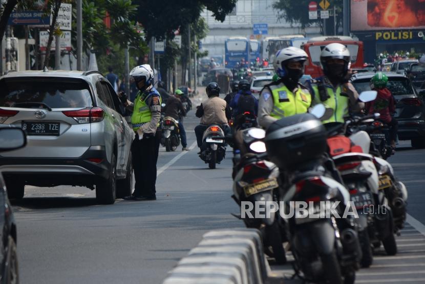 Petugas kepolisian mengamankan kendaraan roda empat di kawasan perluasan ganjil genap Jalan Majapahit, Jakarta, Senin (9/9/2019).