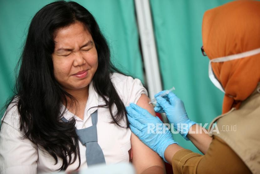 Seorang siswi berekspresi saat diimunisasi difteri pada sosialisasi komitmen pelaksaan kegiatan Outbreak Response Immunization (ORI) Difteri di Sekolah SMAN 33 Jakarta, Jalan Kamal Raya, Jakarta Barat, Senin (11/12).