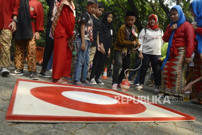 Anak-anak bermain gangsing pada acara Festival Permainan Tradisional Anak Betawi di Hutan Kota Srengseng, Jakarta, Sabtu (3/8).