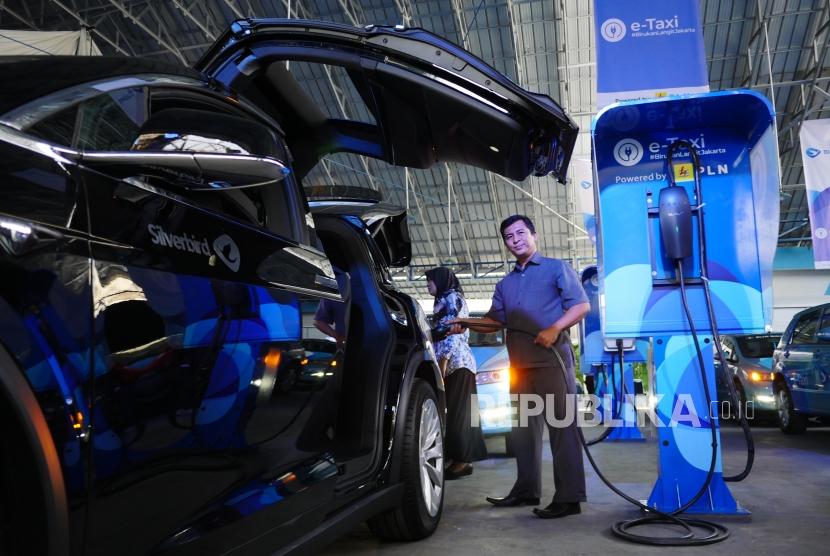 TAKSI LISTRIK. Awak armada e-Taxi Silver Bird memperagakan pengisian baterai mobil Tesla X75 di Port Charging Bluebird di Jakarta, Senin (22/4).