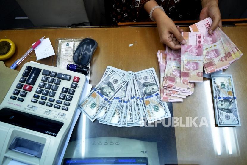 Petugas menghitung mata uang rupiah dan dolar AS di salah satu tempat penukaran uang di Jakarta, Jumat (9/11).