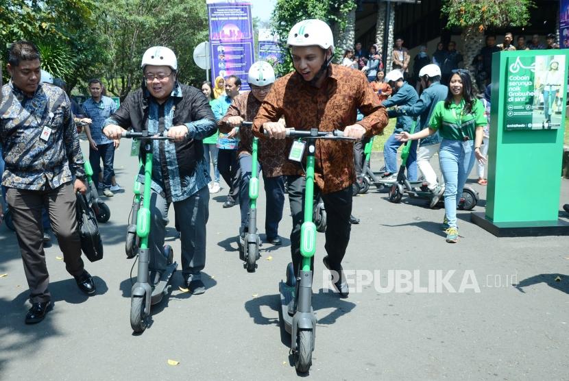 Didampingi Executive Director Grab Indonesia Ongki Kurniawan (kanan) Menteri PPN/Kepala Bappenas Bambang Brodjonegoro (kedua kiri) mencoba moda transportasi e-scooter GrabWheels pada acara ITB CEO NET 2019, di Aula Barat Kampus ITB, Bandung, Selasa (1/10).