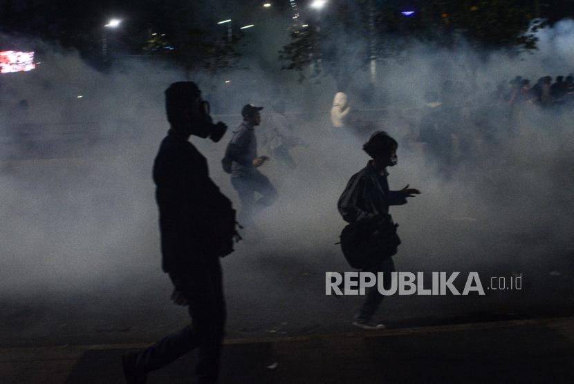 Massa Aksi Mahasiswa Indonesia berlari menghindari gas air mata saat aksi di depan kawasan Jalan Tol Dalam Kota Gatoto Soebroto, Jakarta, Selasa (24/9/2019).