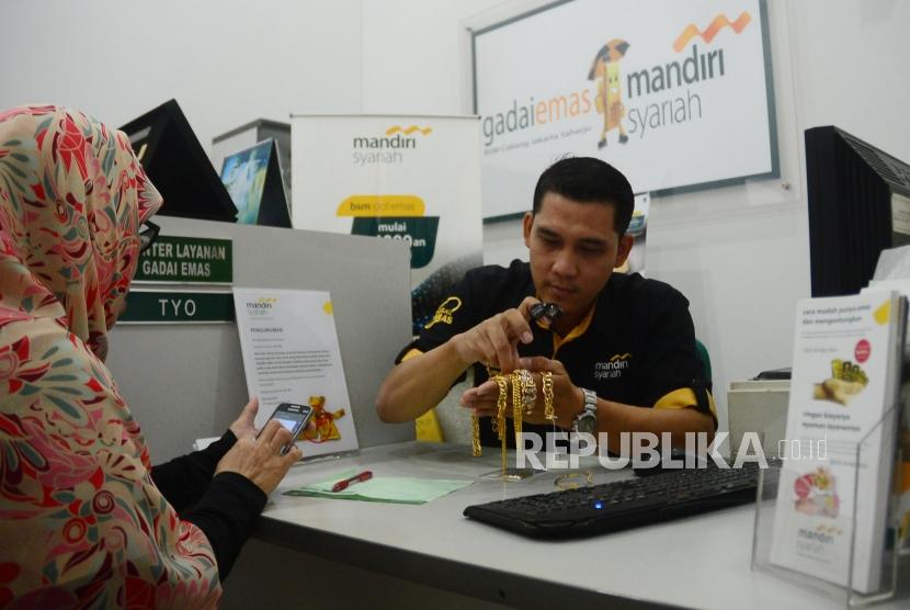 Seorang officer gadai emas Bank Syariah Mandiri (BSM) sedang memberikan penjelasan mengenai produk Gadai Emas Mandiri Syariah kepada seorang nasabah yang akan menggadaikan emasnya di kantor layanan gadai emas BSM di Jakarta, Jumat (9/2).