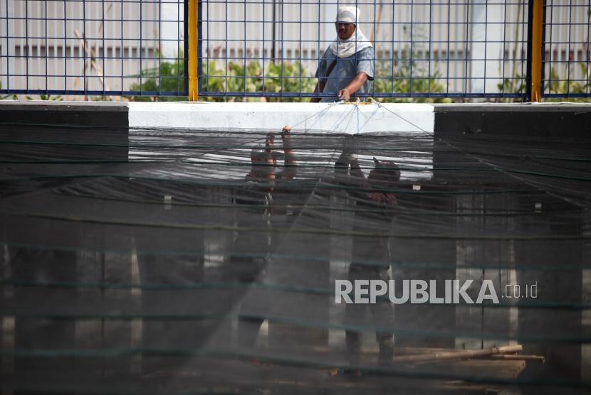 Pekerja memasang jaring (waring) di atas Kali Sentiong, Kemayoran, Jakarta, Jumat (20/7).