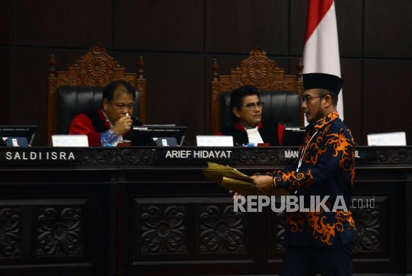 Komisioner KPU Hasyim Asyari saat akan memberikan barang bukti sampul surat suara sah dari pihak termohon pada sidang lanjutan Perselisihan Hasil Pemilihan Umum (PHPU) Pemilihan Presiden (Pilpres) 2019 di Gedung Mahkamah Konstitusi, Jakarta, Kamis (20/6).