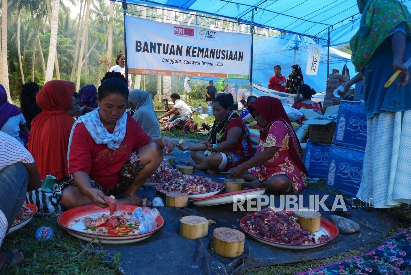 Ibu-ibu dan bapak-bapak pengungsi bergotong royong memotong-motong daging sapi dan memasak di dapur umum Posko Kemanusiaan ACT, di desa Lompio, Kabupaten Sirenja, Donggala Sulawesi Tengah, Ahad (14/10).
