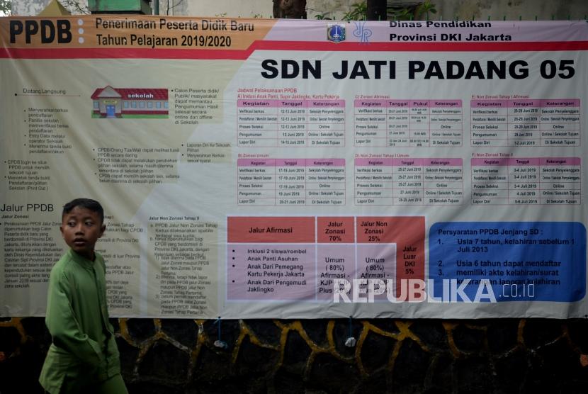 Anak-anak melintas didekat pengumuman Penerimaan Peserta Didik Baru (PPDB) online tahun pelajaran 2019/2020 yang dipajang di SDN Jati Padang 05, Jakarta, Jumat (14/6).