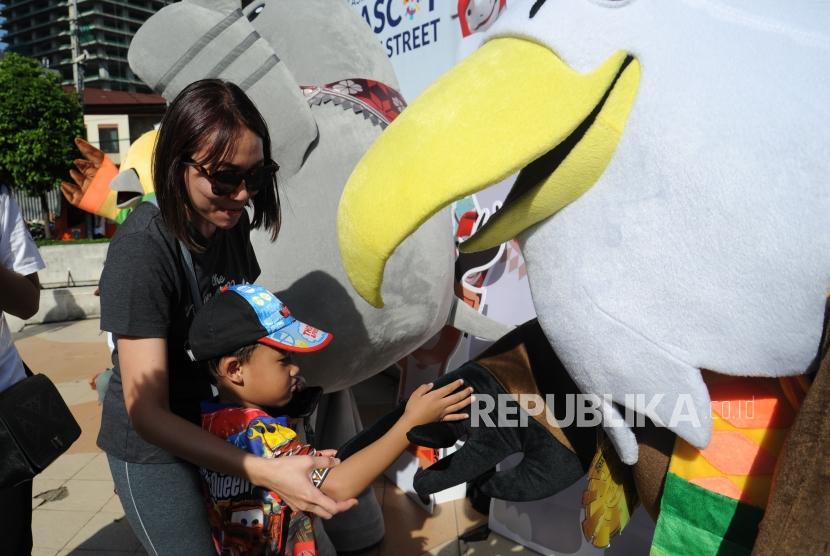 Seorang anak bersalaman dengan maskot Asian Paragames Momo   dikawasan hari bebas berkendara / Car Free Day di Bundaran HI, Jakarta, Ahad (1/4).