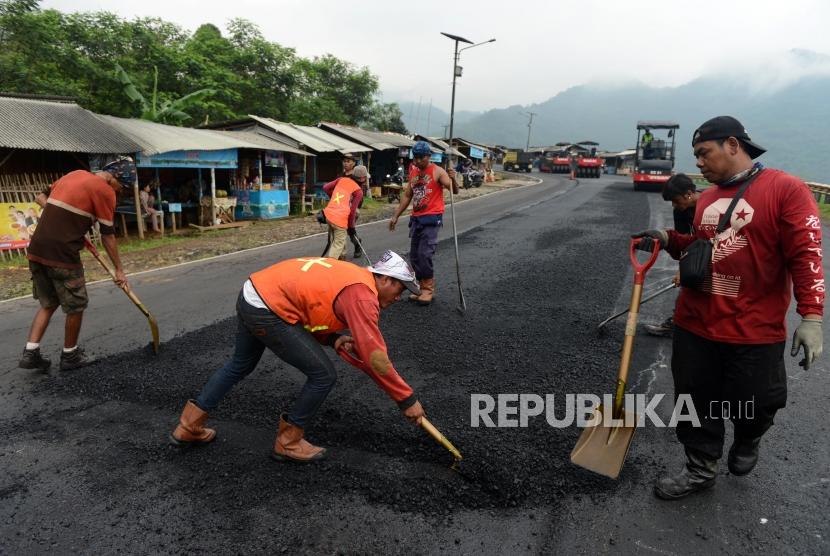 Pekerja saat menyelesaikan perbaikan Jalan Lingkar Gentong, Tasikmalaya, Jawa Barat, Senin (29/4).