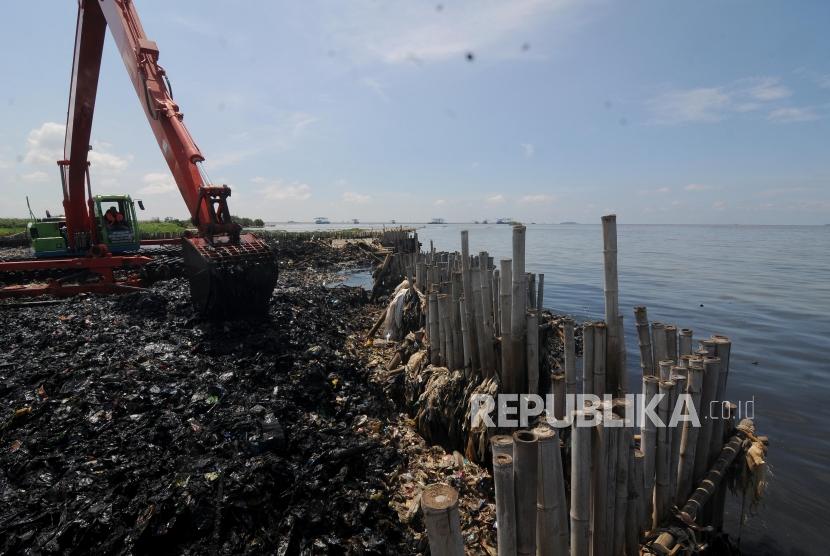 Petugas saat membersihkan sampah yang menumpuk menggunakan alat berat di Muara Angke, Jakarta Utara Senin (19/3).