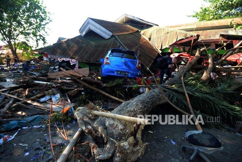 Warga melintasi puing-puing yang terdampak tsunami di kawasan Pantai Talise, Palu, Sulawesi Tengah, Senin (1/10).