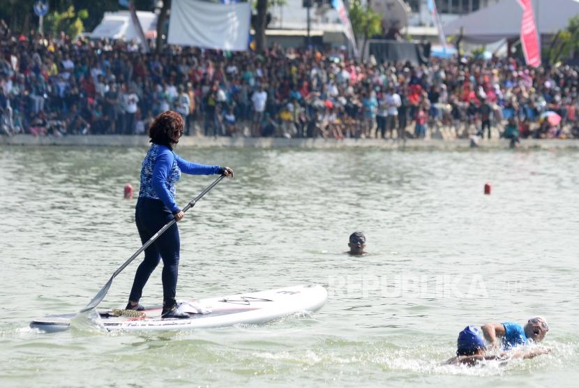 Menteri Kelautan dan Perikanan Susi Pudjiastuti dengan menaiki Paddle Board dan Wagub DKI Jakarta Sandiaga Uno berenang saat kompetisi adu cepat dalam festival Danau Sunter, Jakarta, Ahad (25/2).