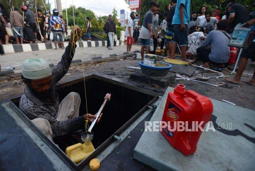 Warga mengambil BBM dari tangki penyimpanan bahan bakar di SPBU, Palu, Sulawesi Tengah, Ahad (30/9).