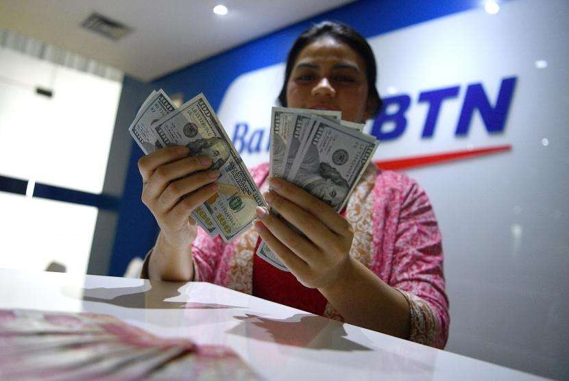 Petugas menghitung uang dolar Amerika Serikat di gerai penukaran mata uang Bank BTN, Jakarta, ilustrasi. BTN menargetkan kredit baru sebesar Rp 1 triliun hingga Juni 2020.