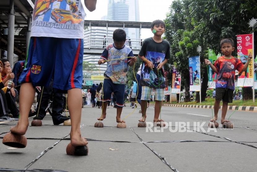 Anak-anak bermain egrang batok kelapa saat car free day di Jalan Jenderal Sudirman, Setiabudi, Jakarta, Ahad (28/1).
