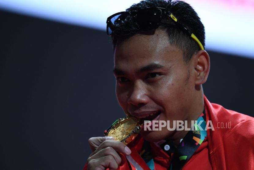 Lifter Indonesia  Eko Yuli  Irawan   mengigit medali emas usai memenangkan  pertandingan di cabang angkat besi putra nomor 62 Kg Asian Games 2018 di Hall A Kemayoran, Jakarta, selasa (21/8).