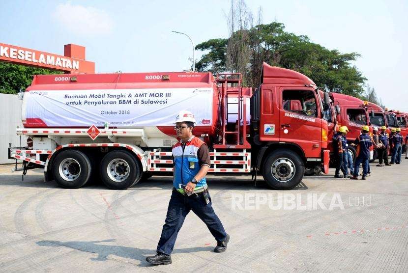 Petugas melintas didekat mobil tangki yang akan mendistribusikan BBM dan Avtur menuju ke Sulawesi, di Terminal Bahan Bakar Minyak (TBBM) Plumpang, Jakarta, Selasa (2/10).