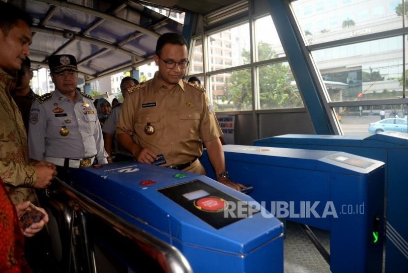 Gubernur DKI Jakarta Anies Baswedan melakukan Tapping (menempelkan) tiket ketika hendak menaiki bus Transjakarta di Halte Dukuh Atas, Jakarta, Selasa (17/10).
