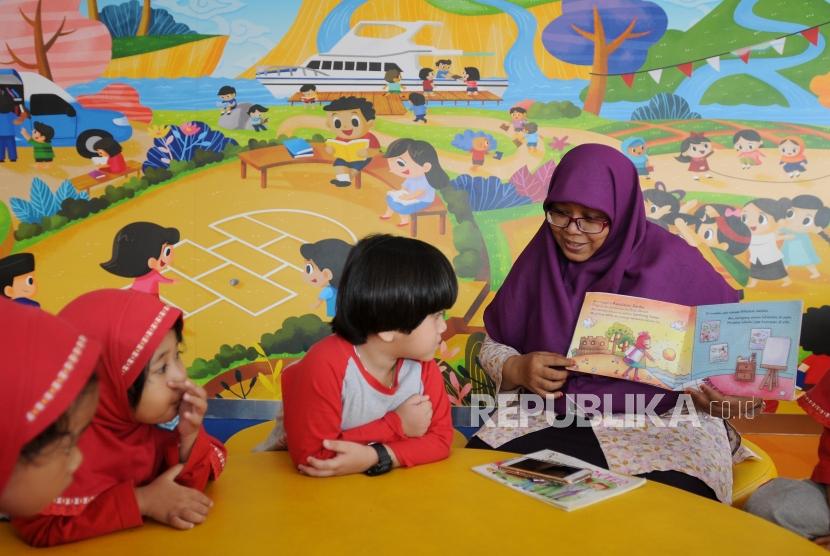 Guru membacakan buku dongeng kepada anak-anak saat melakukan kunjungan ke Perpustakaan Nasional, Gambir, Jakarta, Selasa (10/4).