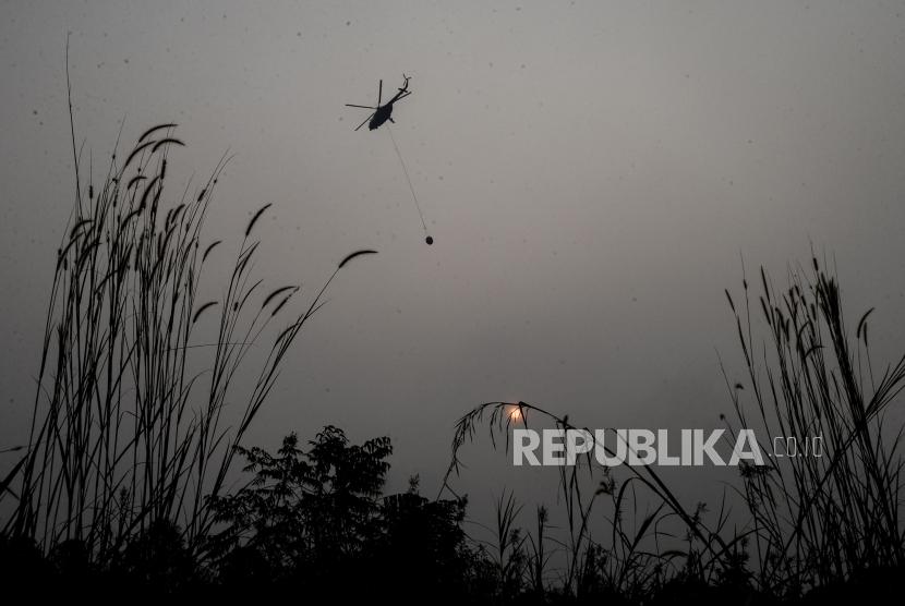 Helikopter BNPB menyiramkan air pada lahan yang terbakar di Desa Rimbo Panjang, Kabupaten Kampar, Riau, Selasa (17/9).