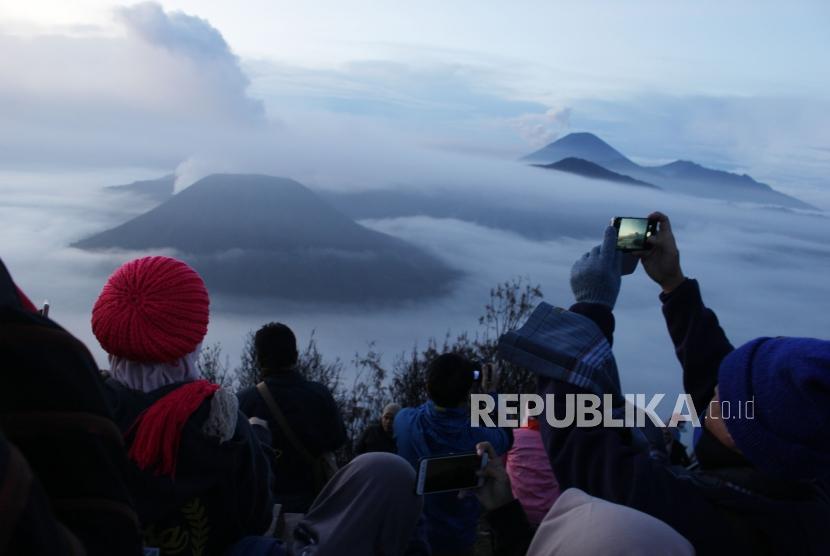 Wisatawan memotret gugusan pegunungan di Taman Nasional Gunung Bromo, Sukapura, Kabupaten Probolinggo, Jawa Timur, Senin (27/11).