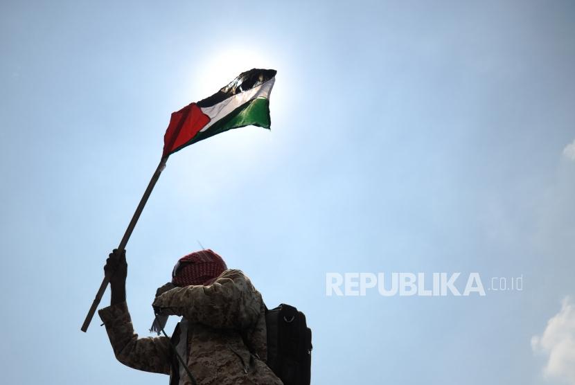 Peserta aksi damai  yang tergabung dari Al- Aqsa Working Group mengibarkan bendera Palestina  saat melakukan aksi damai di  depan kantor Kedubes Amerika Serikat di Jakarta, Selasa (3/4).