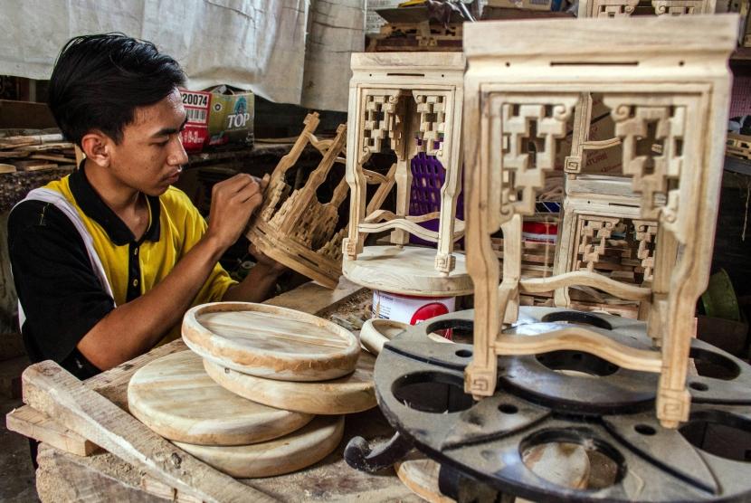Pekerja menyelesaikan pembuatan kerajinan dekorasi rumah dari limbah mebel kayu jati di sebuah industri rumahan di Desa Klampok, Grobogan, Jawa Tengah, Jumat (24/11).