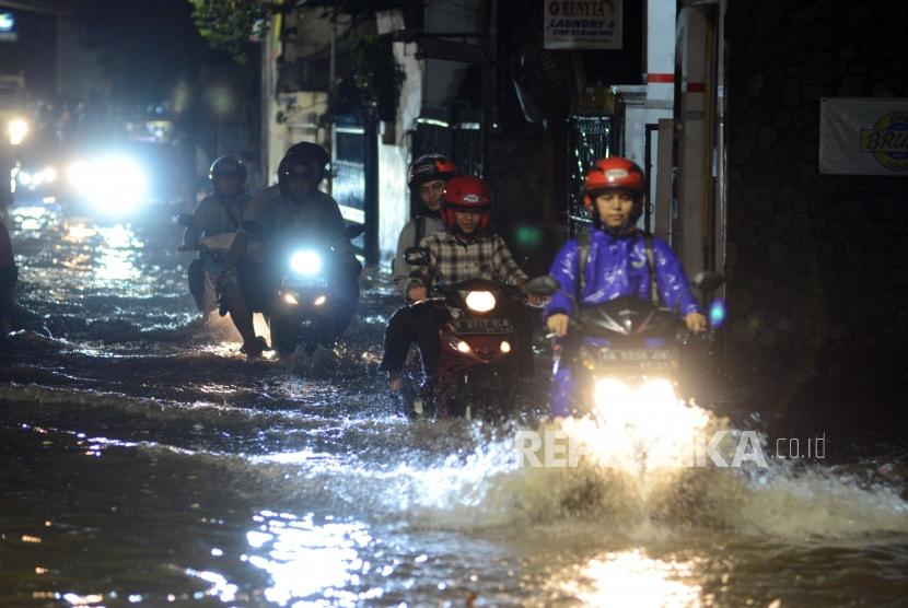 Pengendara motor melintasi genangan air saat terjadi banjir di kawasan Mampang, Jakarta, Kamis (13/12).