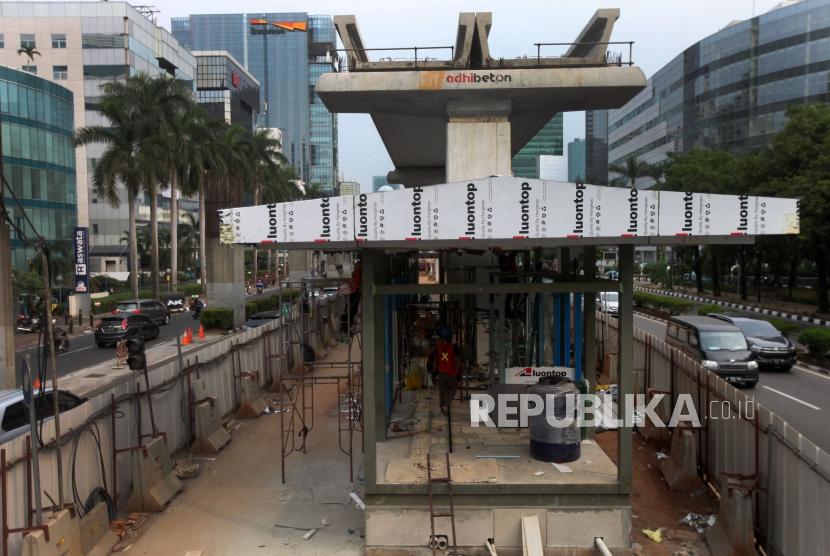 Pekerja menyelesaikan pembangunan halte Transjakarta di bawah pembangunan proyek LRT, Jalan Rasuna Said, Jakarta, Senin (16/7).