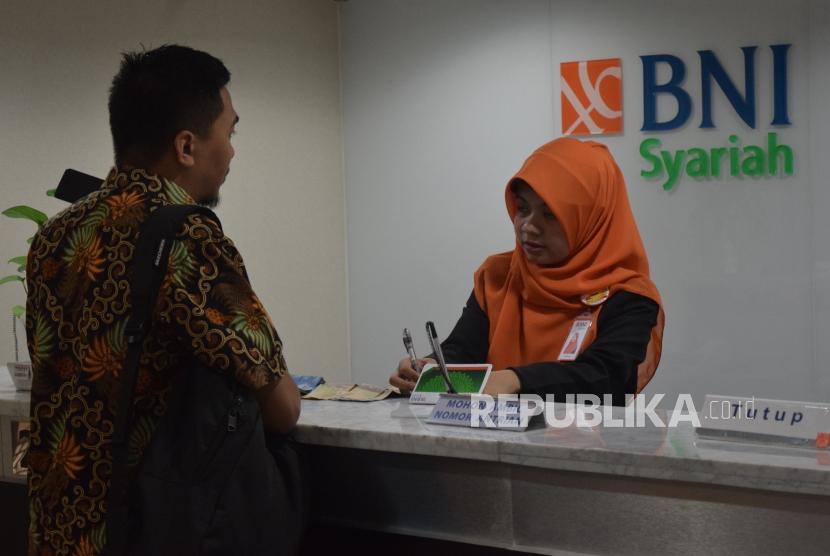 Karyawan melayani transaksi nasabah di kantor layanan BNI Syariah, Jakarta, Senin (5/11).