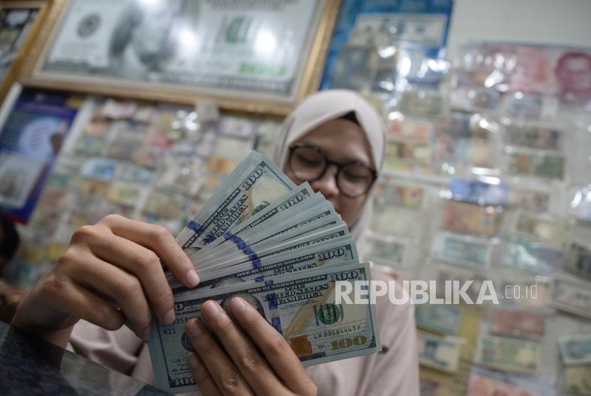 Pegawai menghitung mata uang dolar AS di jasa penukaran mata uang, Jakarta, Ahad (8/4). Bank Indonesia merilis posisi cadangan devisa Indonesia pada akhir Agustus yang meningkat menjadi 137 miliar dolar AS.