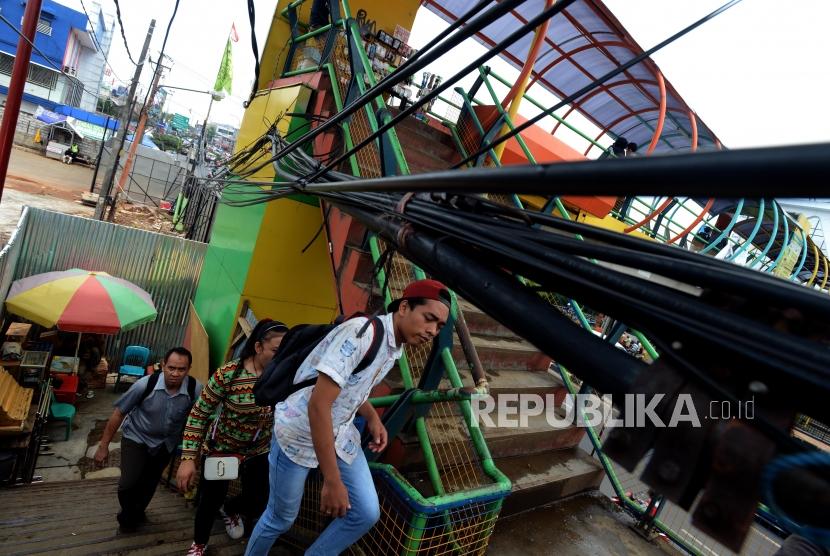Warga berjalan menghindari instalasi kabel yang melintang di Jembatang Penyeberangan Orang (JPO) Margonda, Depok, Jawa Barat, Selasa (23/10).