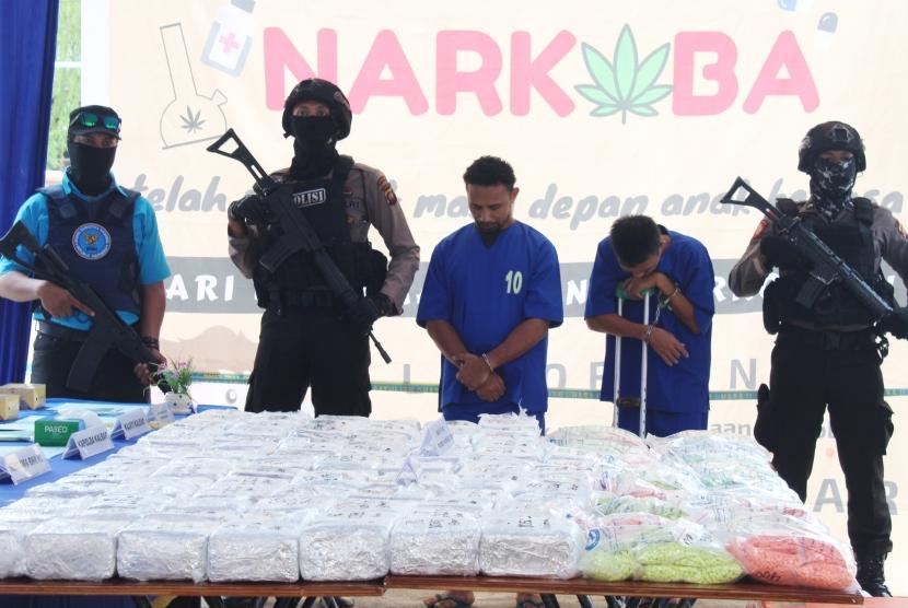 Petugas BNN dan kepolisian berjaga di samping tersangka pengedar narkoba saat dihadirkan pada emusnahan barang bukti narkoba di Kantor BNNP Kalbar di Pontianak, Kalimantan Barat, Kamis (11/4/2019).