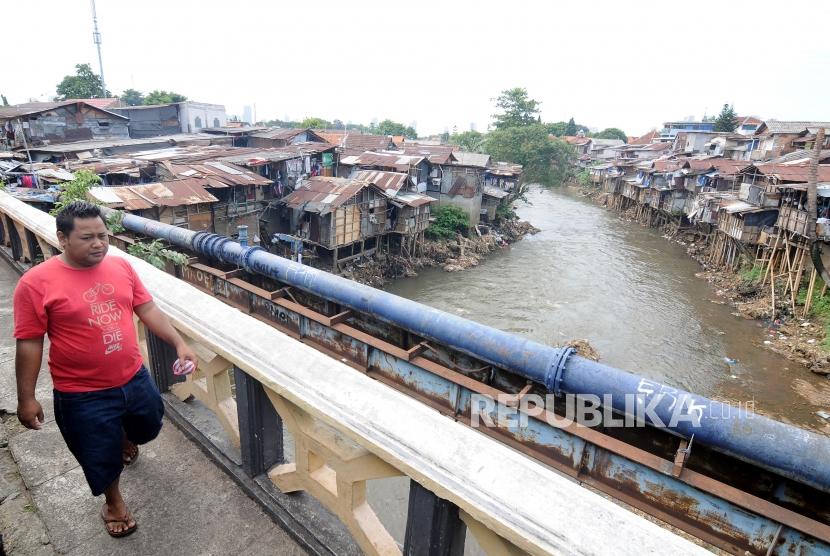 Warga melintas di jembatan yang berada di samping pemukiman bantaran Sungai Ciliwung di kawasan Manggarai, Jakarta Selatan, Senin (8/1).