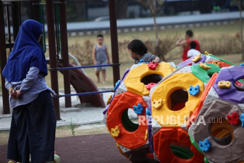 Seorang anak bermain didampingi orang tuanya di area Taman Anak Lapangan Banteng, Jakarta, Kamis (12/7).