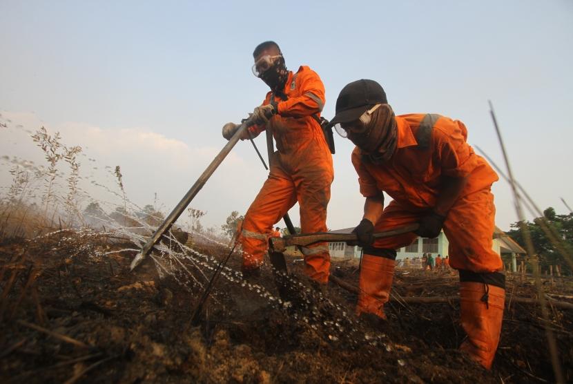 Petugas berupaya memadamkan kebakaran lahan di kawasan Syamsudin Noor, Banjarbaru, Kalimantan Selatan, Sabtu (14/9/2019).