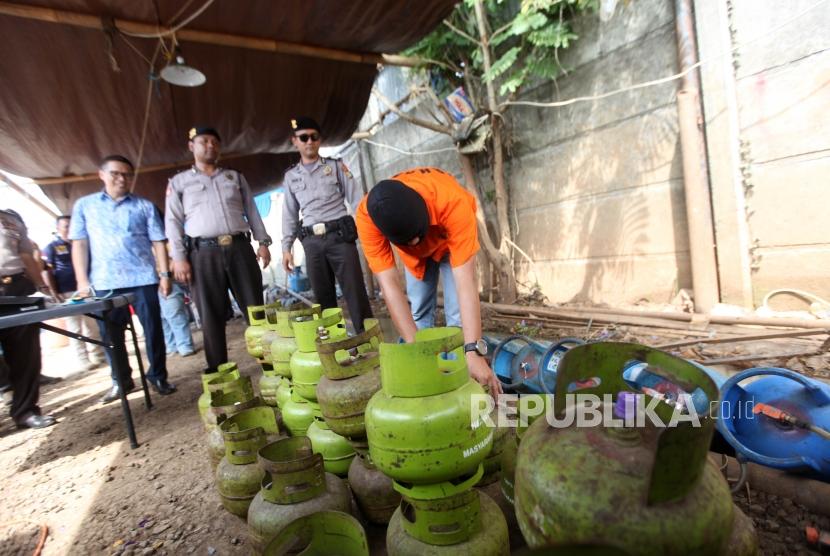 Tersangka menunjukan cara pengoplosan gas saat rilis pengungkapan pabrik pengoplosan tabung gas 3 kilogram ke tabung 12 kilogram dan 50 kilogram di Kawasan Pinang, Tangerang, Banten, Jumat (12/1).