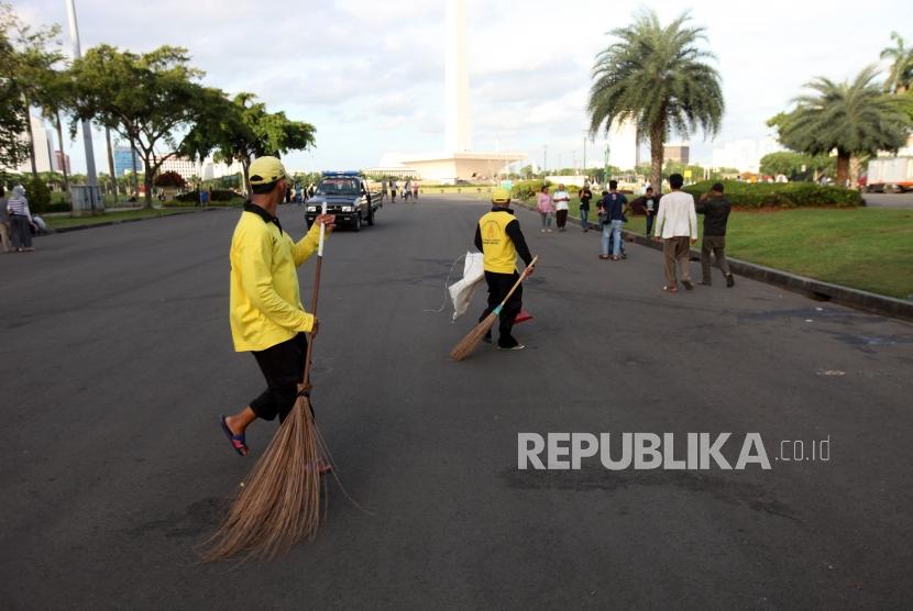 Sejumlah petugas membersihkan sampah di lapangan Monumen Nasional Pasca Aksi Reuni 212, Jakarta, Sabtu (2/12).