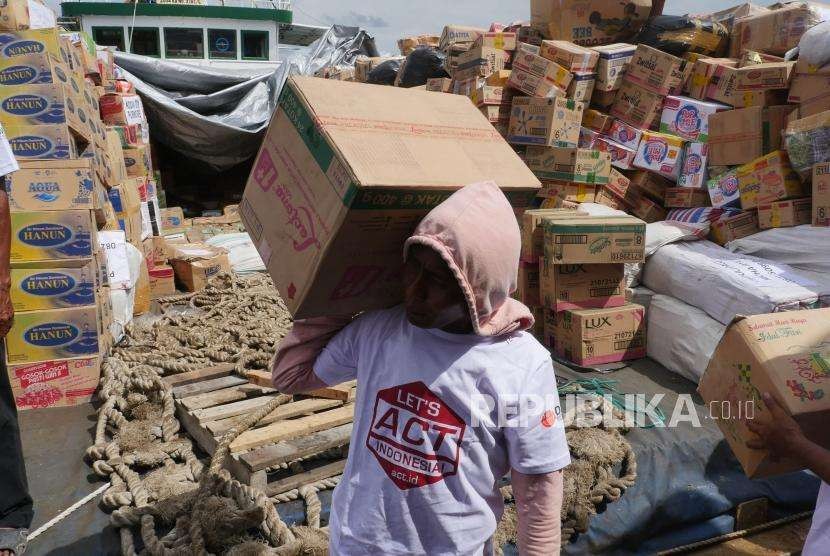 Relawan ACT bersama buruh kapal  bersama-sama mengeluarkan bantuan kemanusiaan dari kapal Kemanusiaaan ACT di Pelabuhan Pantoloan, Palu, Sulawesi Tengah, Sabtu (13/10).