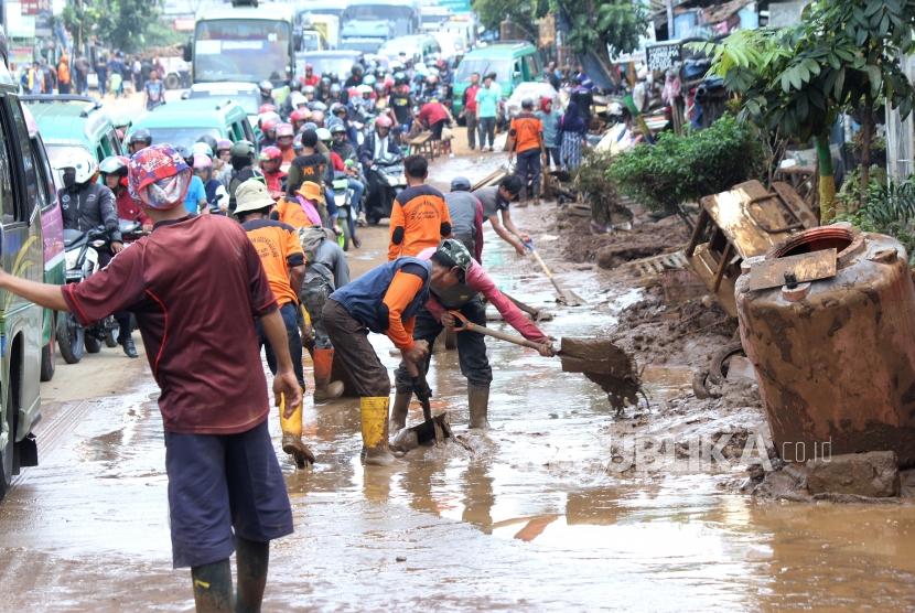 Warga dan petugas kebersihan bergotong-royong membersihkan lumpur sisa banjir yang memenuhi Jalan di kawasan Cicaheum, Kota Bandung, Rabu (21/3).