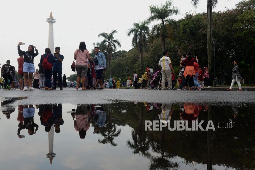 Sejumlah pengunjung saat berwisata di Monumen Nasional (Monas), Jakarta, Jumat (7/6).
