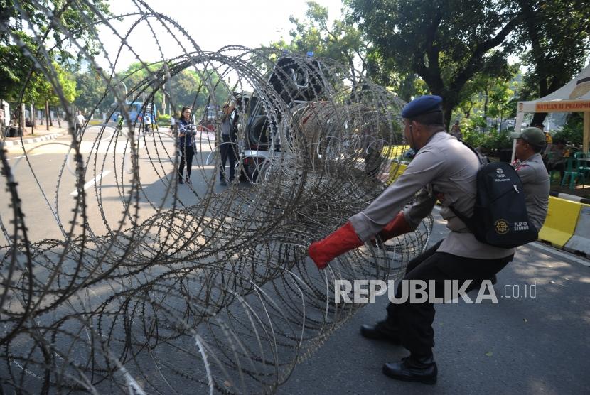 Polisi memasang kawat berduri  di depan Istana Merdeka untuk melakukan pengamanan aksi peringatan hari buruh di Jakarta, Selasa (1/5).