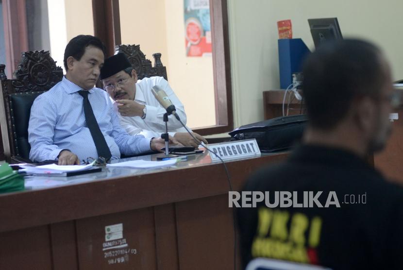 Kuasa Hukum HTI Yusril Ihza Mahendra berbincang dengan mantan juru bicara HTI Ismail Yusanto dalam sidang perdana gugatan HTI terhadap langkah pemerintah yang mencabut status badan hukumnya di PTUN Jakarta, Kamis (23/11).